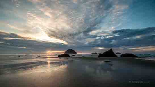 <p>The sunset reflecting off the wet sand with Face Rock in the background</p>