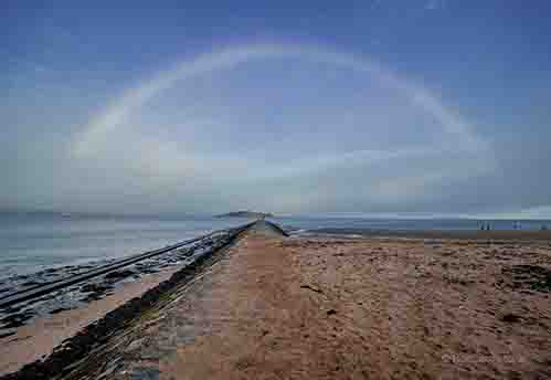 <p>A causeway leading to Crammond Island under a rainbow</p>