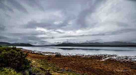 <p>A highland view over a sea lake to hills under clouds</p>