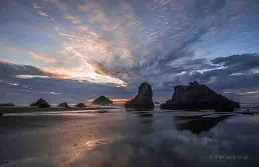 <p>The sunset reflecting off the wet sand with Face Rock in the background</p>