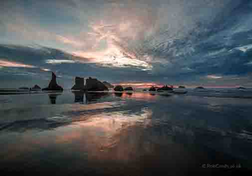 <p>The sunset reflecting off the wet sand with Face Rock in the background</p>